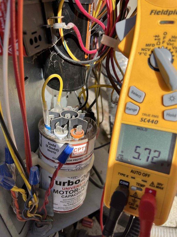 Performed diagnostic evaluation of a single attic-mounted split system for condenser short cycling reported during routine maintenance. Inspected the outdoor unit control compartment and tested the dual-run capacitor with a clamp meter, verifying wiring connections and finding no visible damage, frost, or breakage. Inspected the indoor blower assembly and found heavy rust and corrosion on the blower wheel hub and shaft, which may contribute to airflow and operating issues; further repair recommendations were documented.