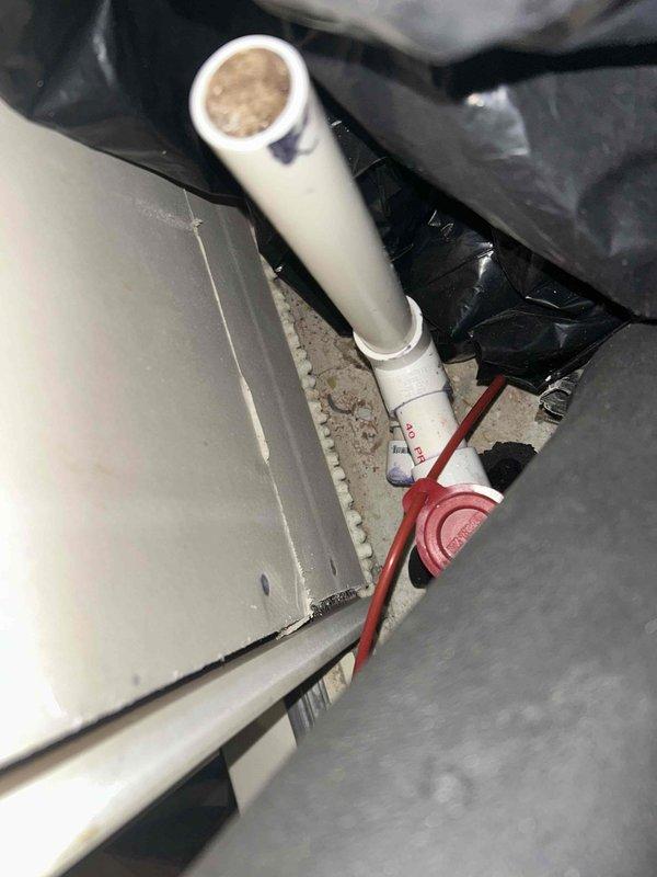 Responded to a no-airflow complaint with loud operating noise on a single attic-mounted split system. Inspection of the air handler showed a dust-laden A-coil with light surface rust on the coil frame fasteners, and a condensate drain line clogged with fibrous debris at the tee/access fitting. The blockage is the likely cause of the system shutdown and restricted operation, and the drain line and pan need to be cleared to restore proper condensate drainage.