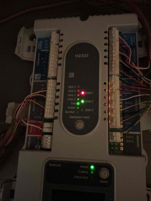 Performed first scheduled maintenance on a 6-month-old 2-zone heat pump system located in the attic, which was clean, safe, and accessible. Inspected the HZ322 zone control panel and verified proper operation, with Home and Config status LEDs active and fan and zone indicators responding correctly. Checked the thermostat wall plate and confirmed secure wire terminations at the R, Rc, C, Y, Y2, W, and W2 terminals. System is performing well with no hot or cold spots reported.