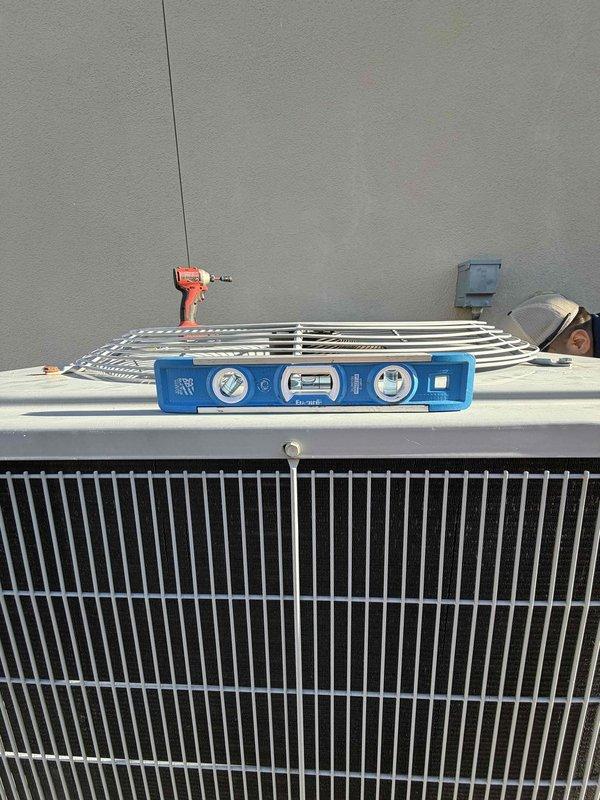 Returned to complete outstanding work on the Carrier condensing unit. Removed the fan guard to access the unit's top section, then used a spirit level to verify the condenser was properly level and stable on its pad. Reinstalled the fan guard, and visual inspection found no signs of frost, ice, corrosion, or physical damage.