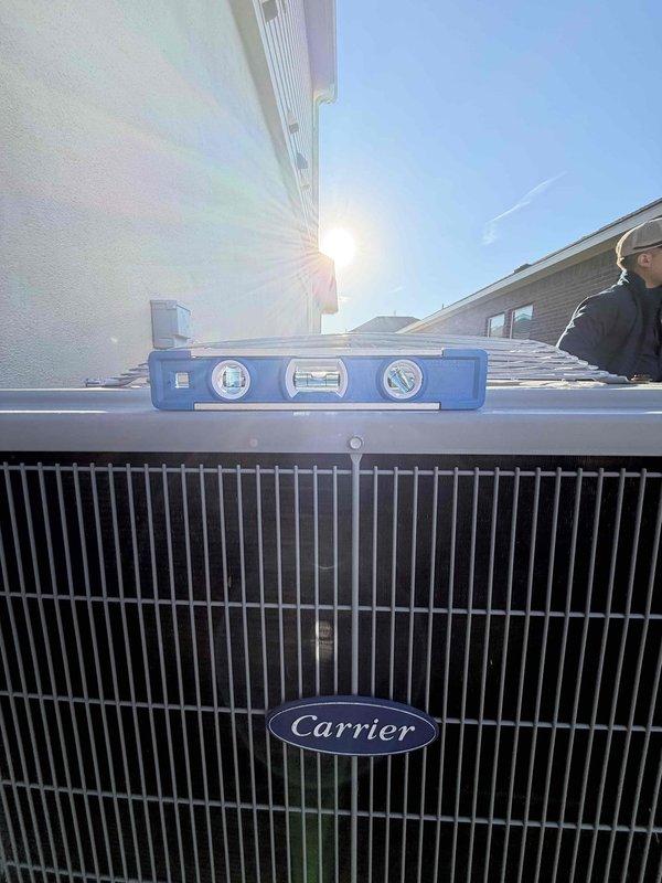 Returned to complete outstanding work on the Carrier condensing unit. Removed the fan guard to access the unit's top section, then used a spirit level to verify the condenser was properly level and stable on its pad. Reinstalled the fan guard, and visual inspection found no signs of frost, ice, corrosion, or physical damage.