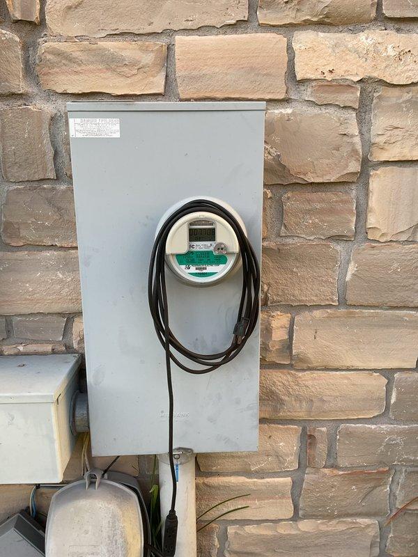 Performed a member electrical maintenance inspection on a 2007-built residence with two breaker boxes (laundry area and exterior near the AC condenser). Visually inspected the exterior utility meter enclosure and service entrance components, finding the digital meter, enclosure, and conduit connections in serviceable condition with no signs of rust, frost, or damage. Also inspected the exterior weatherproof GFCI-type receptacle with in-use cover, which was properly mounted flush and intact.