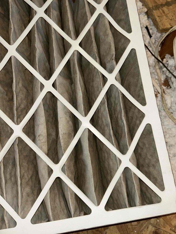 Replaced the heavily soiled pleated air filter at the attic-mounted Carrier air handler; the old media showed significant dust and debris loading that restricted airflow. Installed a new filter of matching size, confirmed proper seating and airflow direction, and left the surrounding duct connections and insulation undisturbed.