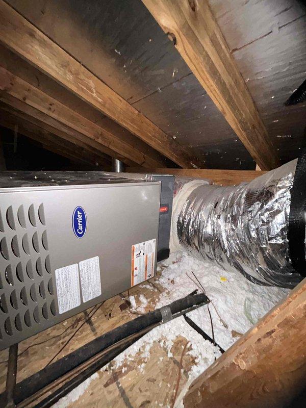Replaced the heavily soiled pleated air filter at the attic-mounted Carrier air handler; the old media showed significant dust and debris loading that restricted airflow. Installed a new filter of matching size, confirmed proper seating and airflow direction, and left the surrounding duct connections and insulation undisturbed.