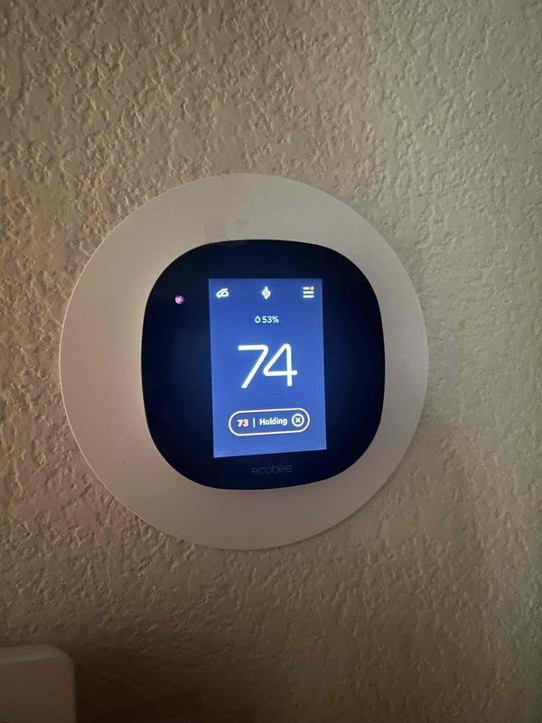 Performed first-time maintenance on two attic-mounted HVAC systems, approximately 2 years old, with attic access confirmed clean, safe, and accessible. Verified ecobee smart thermostat operation at both zones, with displays responding normally and indicating stable indoor temperatures and humidity levels (49–53%) in hold mode. Noted loose patching compound residue around the edge of one thermostat faceplate, which is cosmetic and does not affect operation.