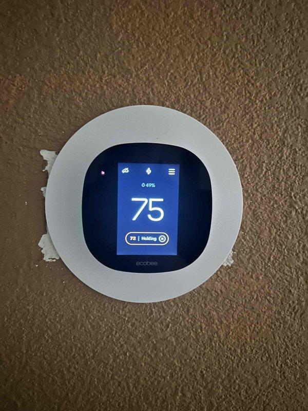 Performed first-time maintenance on two attic-mounted HVAC systems, approximately 2 years old, with attic access confirmed clean, safe, and accessible. Verified ecobee smart thermostat operation at both zones, with displays responding normally and indicating stable indoor temperatures and humidity levels (49–53%) in hold mode. Noted loose patching compound residue around the edge of one thermostat faceplate, which is cosmetic and does not affect operation.