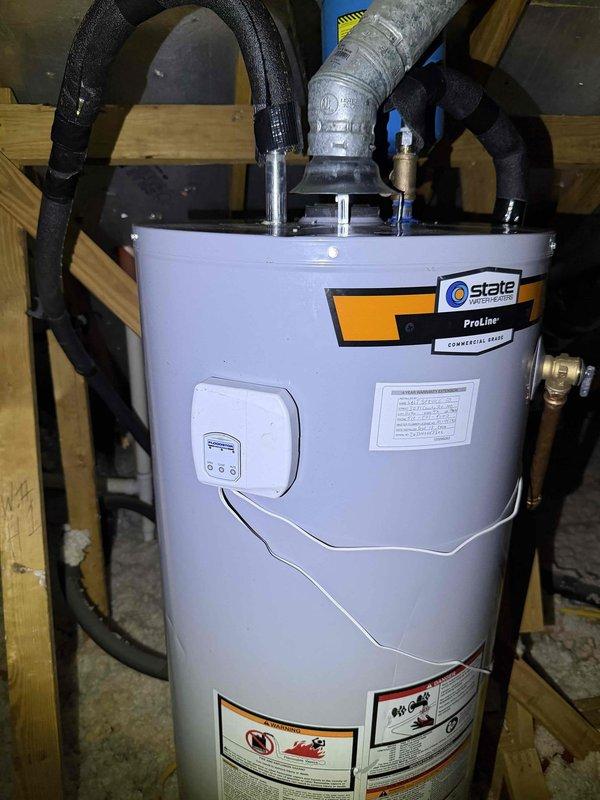 Responded to a no-hot-water complaint and inspected the 16-year-old gas tank-style water heater located in the attic. Evaluated the unit's operation, vent connections, and the installed FloodStop automatic leak-detection shutoff device, including its battery compartment and control status, to diagnose the loss of hot water to the kitchen and upstairs fixtures.