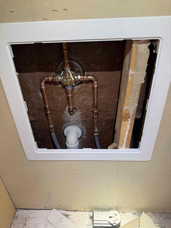 Installed customer-supplied shower valve with associated copper piping connections in bathroom. Created two access panels for future maintenance accessibility. Completed full installation with proper water connections and verified functionality of new shower/tub fixture assembly.