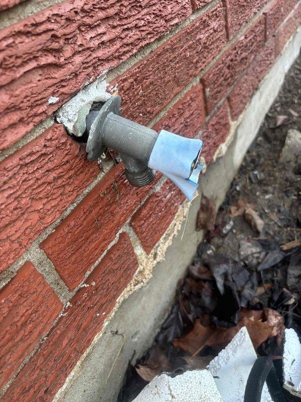 Responded to after-hours service call for broken outside spigot actively leaking from brick wall. Replaced damaged exterior faucet showing deterioration at connection point with new unit, eliminating water flow issue and preventing further moisture damage to foundation area.