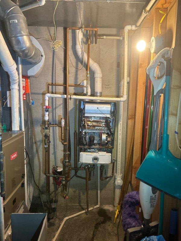 Responded to recall service for reported water heater leak at fitting. Inspection revealed significant corrosion on copper pipe connection with visible green oxidation at brass fitting. Documented maintenance reminder "Flush Annually" present on system components for future reference.