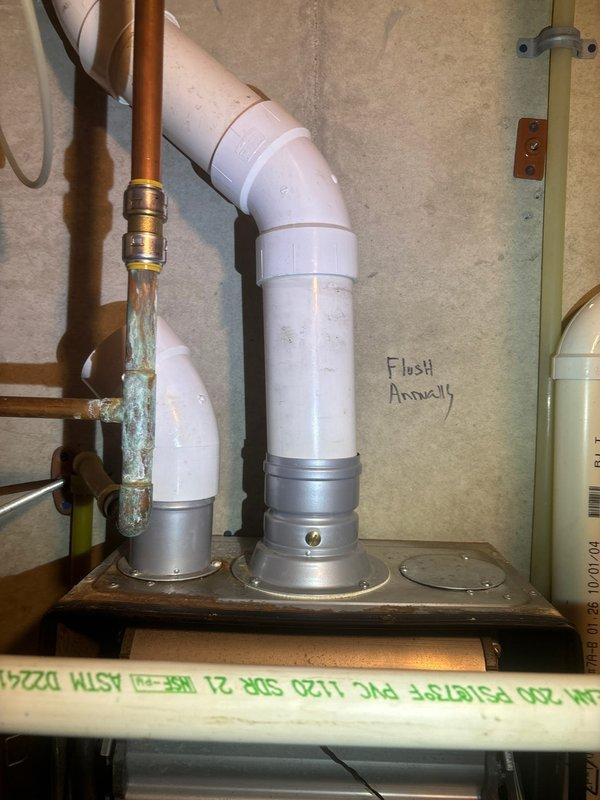 Responded to recall service for reported water heater leak at fitting. Inspection revealed significant corrosion on copper pipe connection with visible green oxidation at brass fitting. Documented maintenance reminder "Flush Annually" present on system components for future reference.