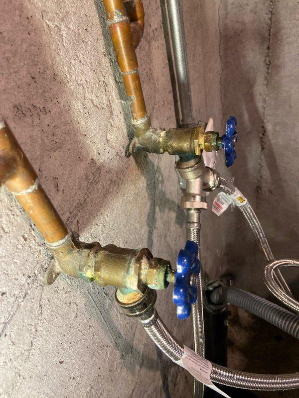 Replaced corroded hot and cold water supply valves serving washing machine in basement. Installed new brass valves with quarter-turn handles and connected flexible stainless steel braided supply lines to complete the installation.
