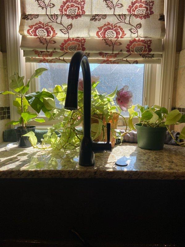 Successfully installed customer-supplied black kitchen faucet with tall, arched design on granite/stone countertop. Properly connected water supply lines through existing access point and verified functionality of the new fixture. All connections were secured and tested to ensure no leaks.