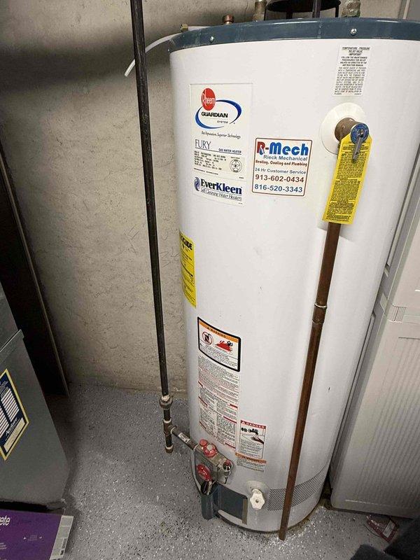 Responded to service call for washing machine drain backup in basement. Upon inspection, determined the issue was not related to the washing machine drain but instead identified problems with the water heater system. Documented the Rheem Guardian "Fury" unit's condition and inspected the piping configuration, noting proper venting and supply line connections were intact and functioning normally.