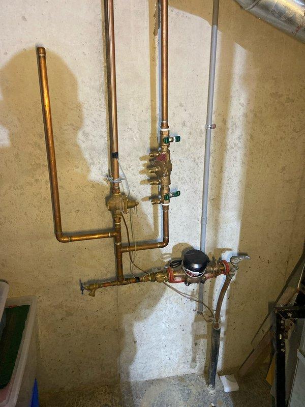 Conducted a comprehensive whole-home plumbing inspection as requested by customer. Examined water heater system with associated copper piping, expansion tank, and PVC drainage components in utility area, noting all were in normal working condition. Inspected main water supply configuration including copper pipe network, brass valves, and water meter/pressure regulator, observing some historical water staining around pipe connections but no active leaks or immediate concerns.