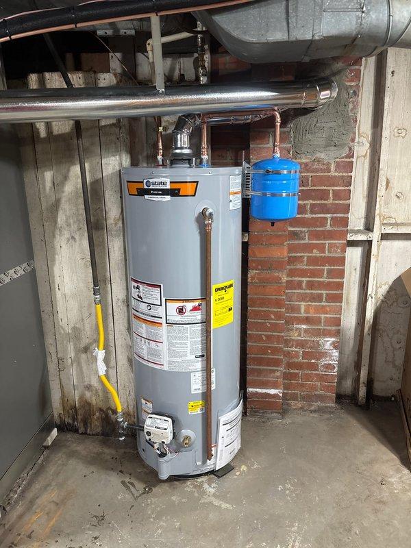Successfully installed a 50-gallon State gas water heater with proper connections to existing copper plumbing system. Installed a blue thermal expansion tank on the supply line to prevent pressure buildup. Completed all necessary gas line connections and verified proper venting through the existing metal flue pipe for safe operation.