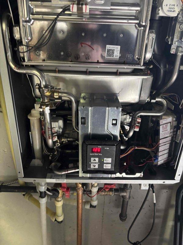 Replaced defective hot water servo valve assembly and installed new relief pipe assembly on tankless water heater. System diagnostic confirmed proper operation with normal temperature readings on digital display panel. All connections secure and system functioning as designed.