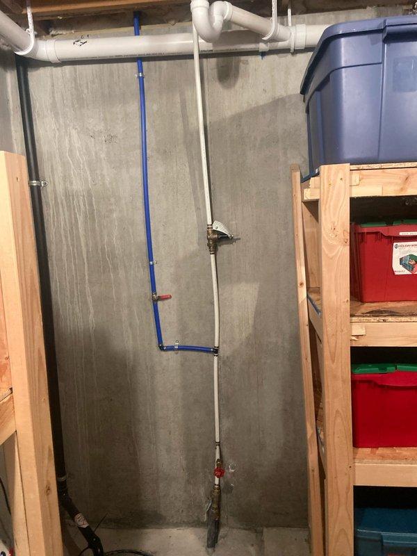 Conducted site assessment for potential installation of US Water Systems softeners/filters. Inspected existing plumbing configuration in utility area, documenting the current PVC pipe layout with horizontal runs near ceiling and vertical sections connecting to main water supply. Evaluated available space and mounting options for new water treatment system installation.