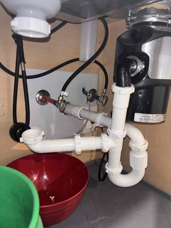 Responded to service call for leaking pipes under kitchen sink. Upon inspection, identified loose connection at P-trap assembly connected to garbage disposal unit. Disassembled affected PVC components, cleaned pipe threads, applied new plumber's tape, and reassembled with proper torque. Tested repair by running water through system and confirmed leak was successfully resolved.
