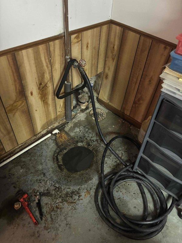Responded to service call for basement drain backing up during washing machine use. Inspected the basement drainage system including sump pump installation and associated plumbing. Cleared clog in the main drain line and verified proper drainage function by running test cycles, resolving the backup issue that was causing water damage to the wooden wall paneling and concrete floor.