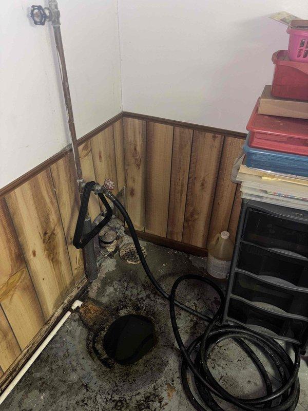 Responded to service call for basement drain backing up during washing machine use. Inspected the basement drainage system including sump pump installation and associated plumbing. Cleared clog in the main drain line and verified proper drainage function by running test cycles, resolving the backup issue that was causing water damage to the wooden wall paneling and concrete floor.