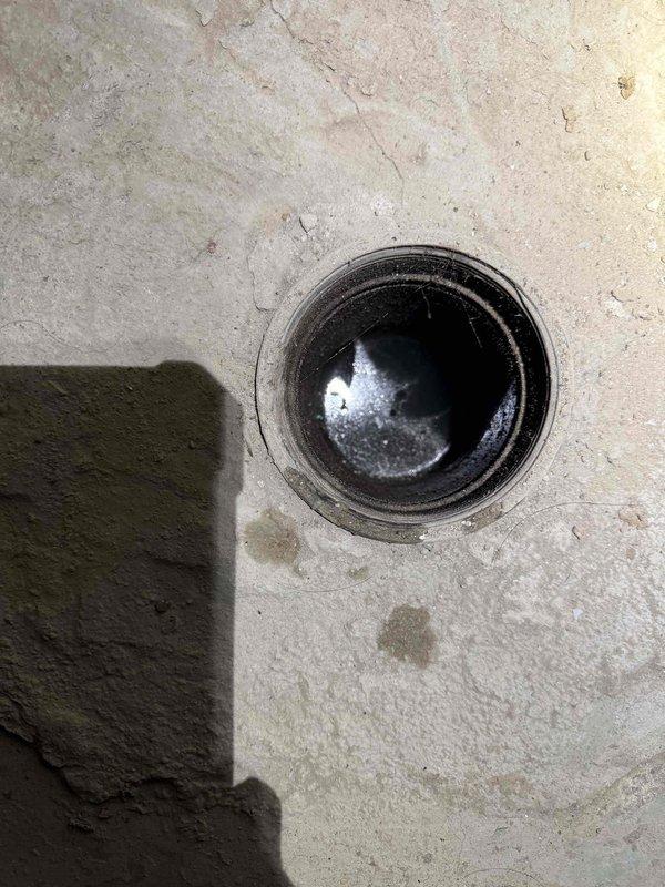 Cleaned main drain line in the basement that was backing up. Visual inspection revealed significant corrosion and deterioration of the drain pipe with standing water present. Successfully cleared blockage and restored proper drainage function.