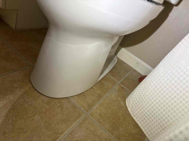 Successfully installed three Toto Drake toilets in the bathroom, securing each fixture properly to the beige tile flooring with mounting bolts. All units were tested for proper operation and sealing, with no leaks detected at the base connections.