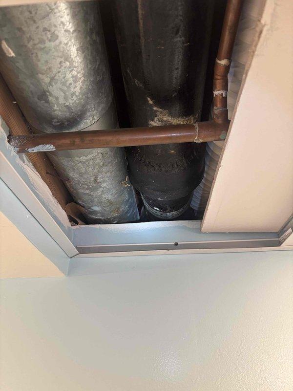 Responded to service call for broken cast iron pipe in basement ceiling. Upon inspection, discovered corroded section of cast iron drain pipe with visible rust patches running parallel to HVAC ductwork between ceiling joists. Removed ceiling tiles for access, repaired damaged section of pipe, and restored proper drainage function.