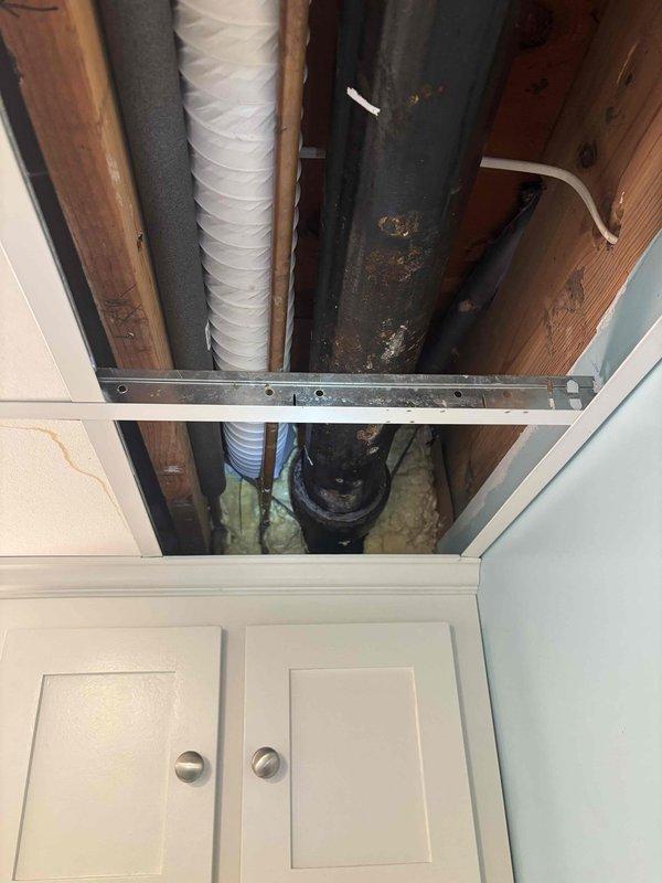 Responded to service call for broken cast iron pipe in basement ceiling. Upon inspection, discovered corroded section of cast iron drain pipe with visible rust patches running parallel to HVAC ductwork between ceiling joists. Removed ceiling tiles for access, repaired damaged section of pipe, and restored proper drainage function.