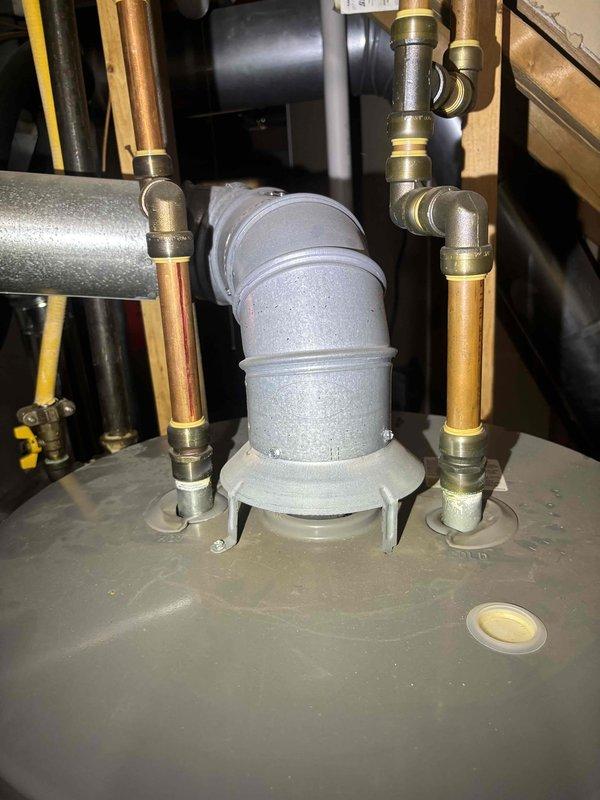 Inspected reported moisture at flute joint on Ruud water heater system. Examined copper pipe connections and PVC fittings throughout the utility room installation. No active leaks detected during inspection; system currently operating normally with all connections secure.