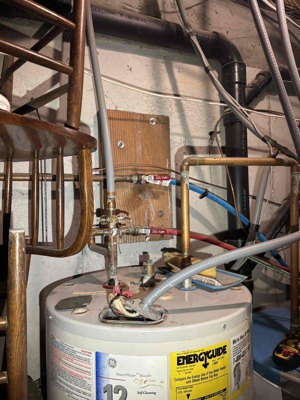 Repaired significant leak at copper pipe connection near main water shutoff valve, evidenced by severe verdigris corrosion and mineral buildup. Removed and replaced failing electric water heater with customer-provided unit, ensuring proper installation of all connections including copper and PEX piping, pressure relief valve, and appropriate valves for isolation.