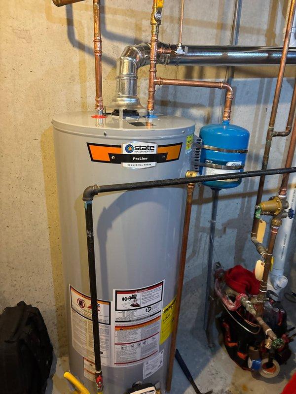 Installed new 50 gallon State ProLine natural gas water heater with associated copper piping and blue expansion tank mounted vertically. Completed all necessary connections including gas line, water supply lines, and proper venting to ensure safe and efficient operation per manufacturer specifications.