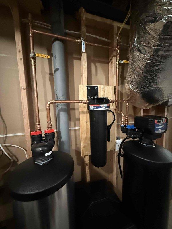 Successfully installed customer-supplied water softener system adjacent to outlet near Wi-Fi equipment. Tapped into main water line after the first hose bib to ensure proper functionality, then ran main feed to softener and connected softened water back into the cold side feed near the water heater. System was properly programmed and initial flush completed to remove shipping debris from the system.