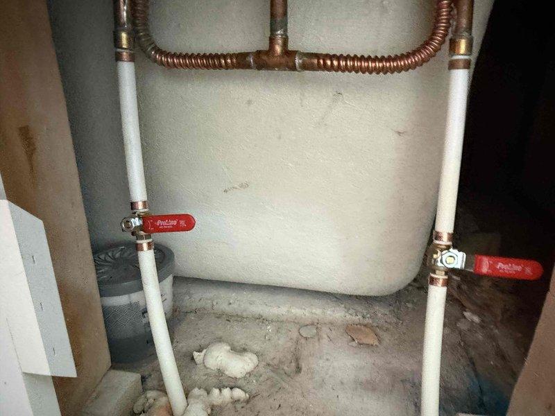 Completed installation of ball valve in residential plumbing system, involving copper supply lines and PVC piping. Successfully installed and tested new shut-off valves with red handles on both sides of the installation, providing improved water flow control for the homeowner.