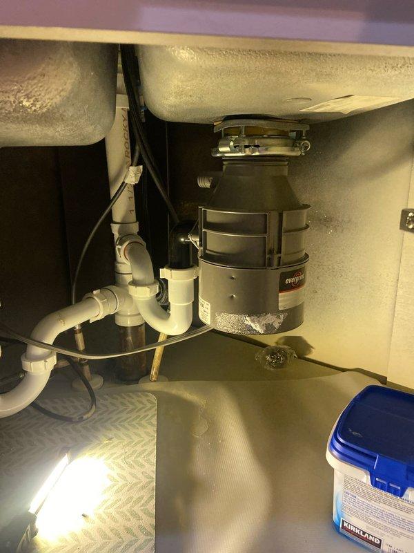Responded to service call for non-operational garbage disposal in kitchen sink. Upon inspection, identified an InSinkErator unit that required reset. Accessed reset button on underside of unit, cleared minor debris from disposal chamber, and verified proper operation after reset. Unit now functioning correctly with no leaks observed at connections.