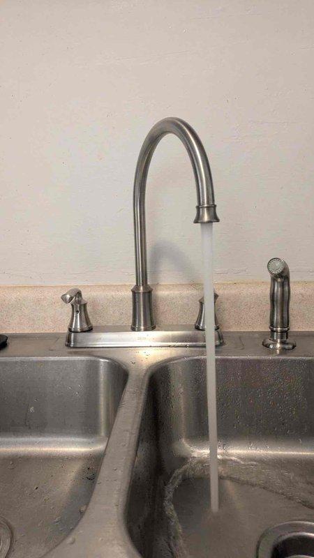 Successfully completed kitchen faucet replacement as requested by customer. Installed new customer-supplied faucet with dual control knobs and separate sprayer attachment onto double-basin stainless steel sink. Tested water flow and confirmed proper operation with no leaks.
