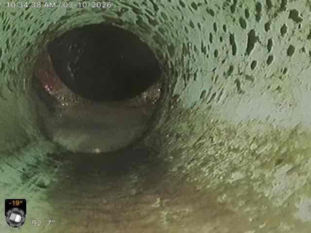 Performed camera inspection of main line in response to a second opinion request regarding a potential line break near city connection. Inspection revealed significant buildup of debris and mineral deposits on pipe walls with partial blockage visible. Inspection footage documented deteriorating pipe condition with mottled surfaces and moisture accumulation, confirming issues that require attention before connecting to municipal system.