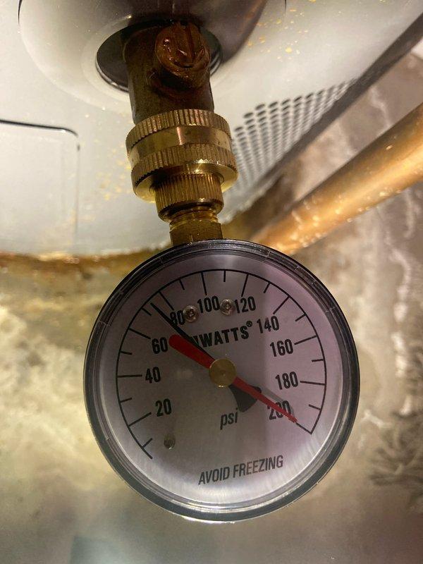 Completed inspection of existing water heater system in basement for replacement estimate. System includes a RUUD tank water heater with copper piping, expansion tank, and red-handled valve. Pressure gauge testing showed reading of approximately 80-90 PSI, which is at the upper acceptable limit for residential plumbing systems.