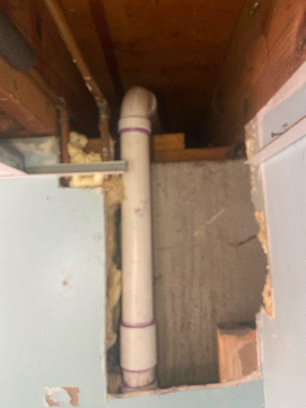 Completed removal of deteriorated cast iron and lead drain lines throughout the residence, requiring strategic access through bathroom fixtures, vanity, basement ceiling, and sheetrock. Installed new PVC drainage system with proper venting, including new toilet flanges and p-trap replacement for tub (eliminating drum trap), with main stack tie-in requiring rerouting through garage area to accommodate larger PVC diameter. Documented installation of vertical PVC drain pipe with proper purple primer markings at connection points and successful pipe routing through confined structural spaces.