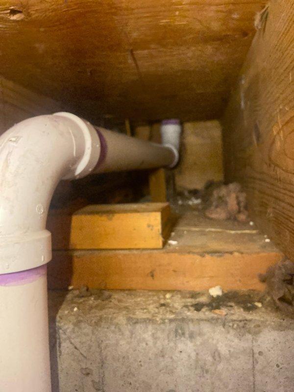 Completed removal of deteriorated cast iron and lead drain lines throughout the residence, requiring strategic access through bathroom fixtures, vanity, basement ceiling, and sheetrock. Installed new PVC drainage system with proper venting, including new toilet flanges and p-trap replacement for tub (eliminating drum trap), with main stack tie-in requiring rerouting through garage area to accommodate larger PVC diameter. Documented installation of vertical PVC drain pipe with proper purple primer markings at connection points and successful pipe routing through confined structural spaces.