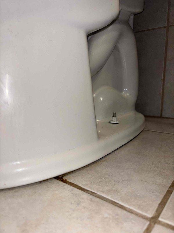 Responded to service call for potential sump pump connection line issue. Upon inspection, found one toilet leaking at the base and another toilet with stability issues. Photographed both fixtures to document the conditions of the porcelain bases and floor mounting hardware, which revealed loosened bolts at the base of one toilet and evidence of water damage around the other.