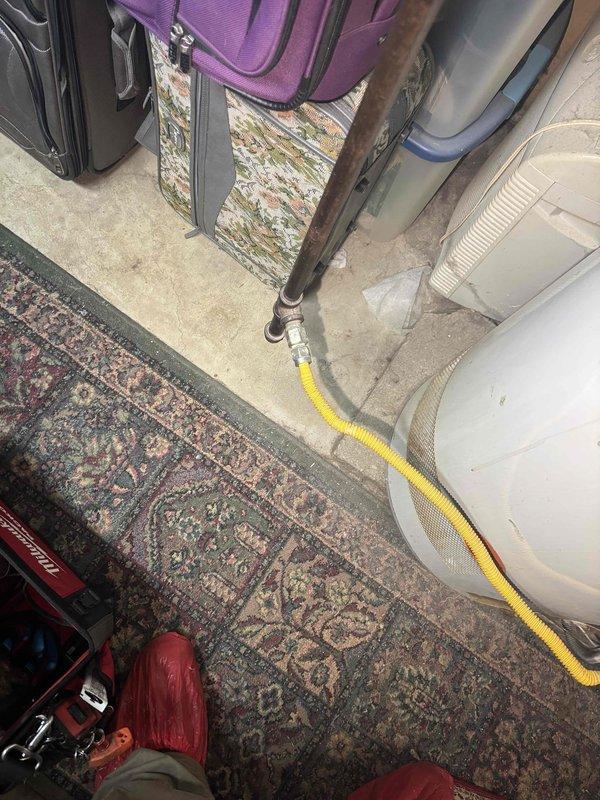 Diagnosed water heater with pilot light failure. Inspected blue cylindrical tank in basement utility area with connecting PVC plumbing. Serviced pilot assembly to restore proper ignition, successfully resolving the no hot water issue.