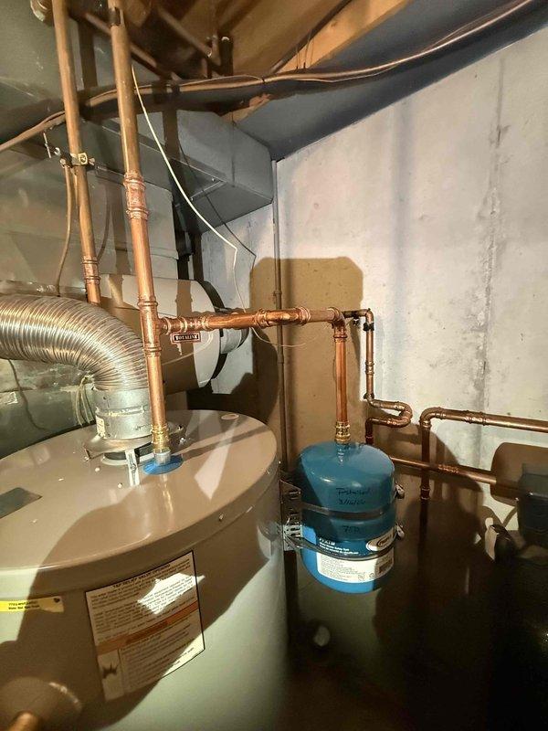Installed new 50-gallon gas water heater with code-compliant copper piping and expansion tank in utility area. System includes proper ventilation with flexible metallic ducting and all necessary brass fittings. Installation complete and unit functioning as designed.
