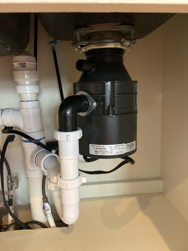 Successfully diagnosed and repaired leaking garbage disposal in kitchen sink. Installed new disposal unit with properly connected PVC drain pipes and P-trap configuration. Tested system to ensure complete resolution of leak with all connections secure and functioning correctly.