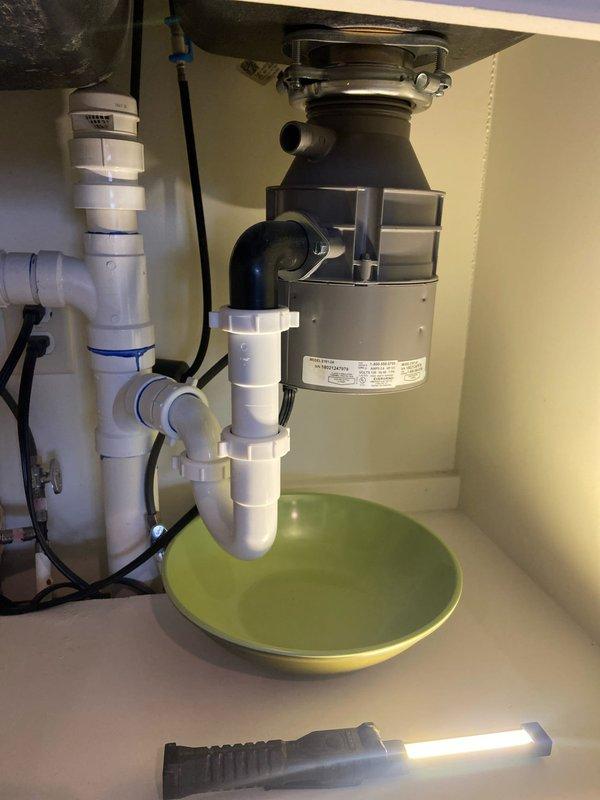 Successfully diagnosed and repaired leaking garbage disposal in kitchen sink. Installed new disposal unit with properly connected PVC drain pipes and P-trap configuration. Tested system to ensure complete resolution of leak with all connections secure and functioning correctly.