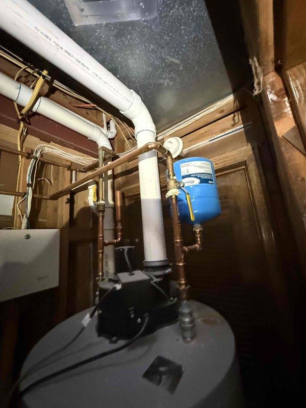 Performed water leak detection service, identifying mineral buildup and corrosion at the connection point between supply line and toilet tank fitting. Inspected basement plumbing system including water heater, expansion tank, and associated copper/PVC piping to locate source of leak.