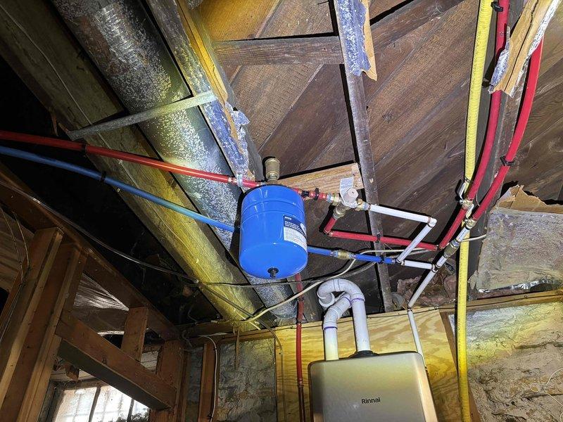 Successfully installed a Rinnai RE199IN tankless water heater system in customer's property. Completed the mounting and connection of all necessary plumbing components, including PEX supply lines and a blue expansion tank to the ceiling joists. System was properly secured in the unfinished basement area with all connections verified for proper operation.