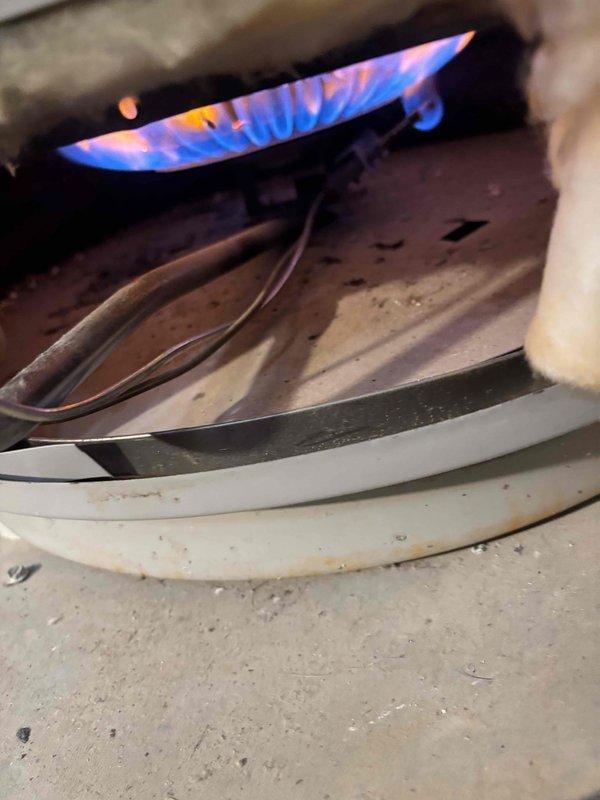 Responded to service call for non-operational water heater. Diagnosed issue with gas burner assembly, cleaned flame sensor and burner components to remove accumulated grime affecting ignition. Verified proper operation after service with even blue flame pattern and confirmed proper water heating functionality.