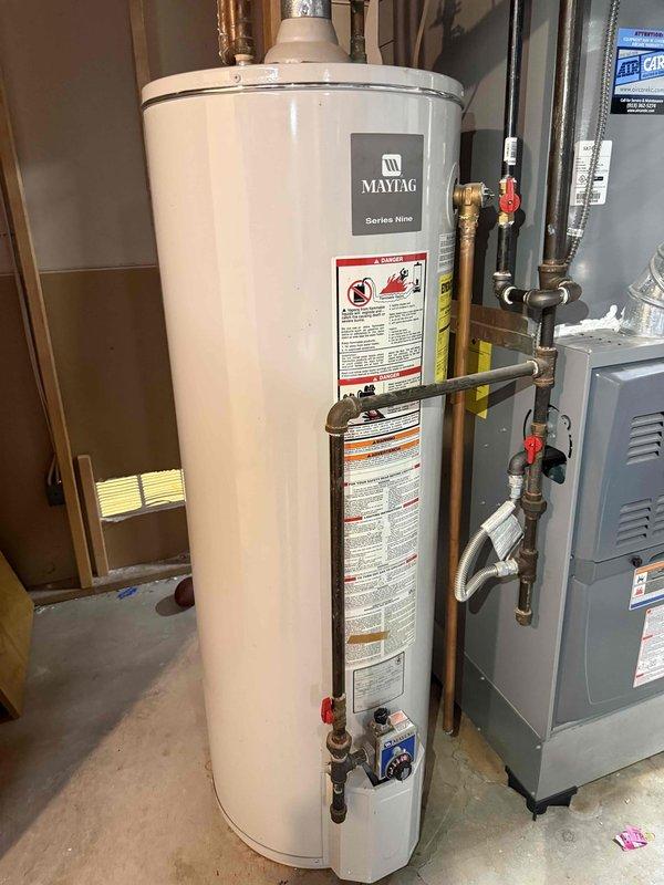 Conducted water heater replacement estimate for aging Maytag Series Nine unit showing significant corrosion and mineral deposits on connecting copper pipes. Assessed existing installation setup including pressure relief valve, shutoff valves, and ventilation system for potential upgrade to either new tanked or tankless model. Photos documented current system condition and space constraints for proper replacement recommendation.