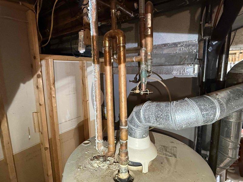 Conducted water heater replacement estimate for aging Maytag Series Nine unit showing significant corrosion and mineral deposits on connecting copper pipes. Assessed existing installation setup including pressure relief valve, shutoff valves, and ventilation system for potential upgrade to either new tanked or tankless model. Photos documented current system condition and space constraints for proper replacement recommendation.